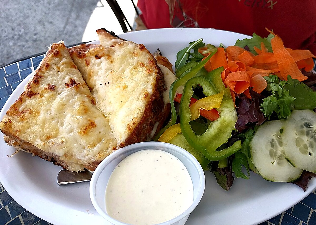 A bronzed croque monsieur with green salad, bakery-style