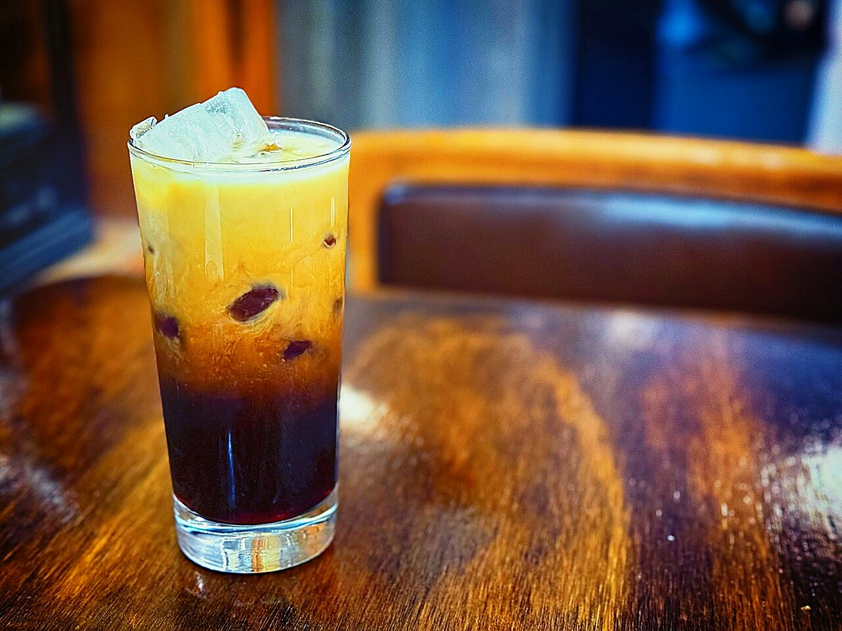 A tall layered iced coffee with milk over ice in a glass