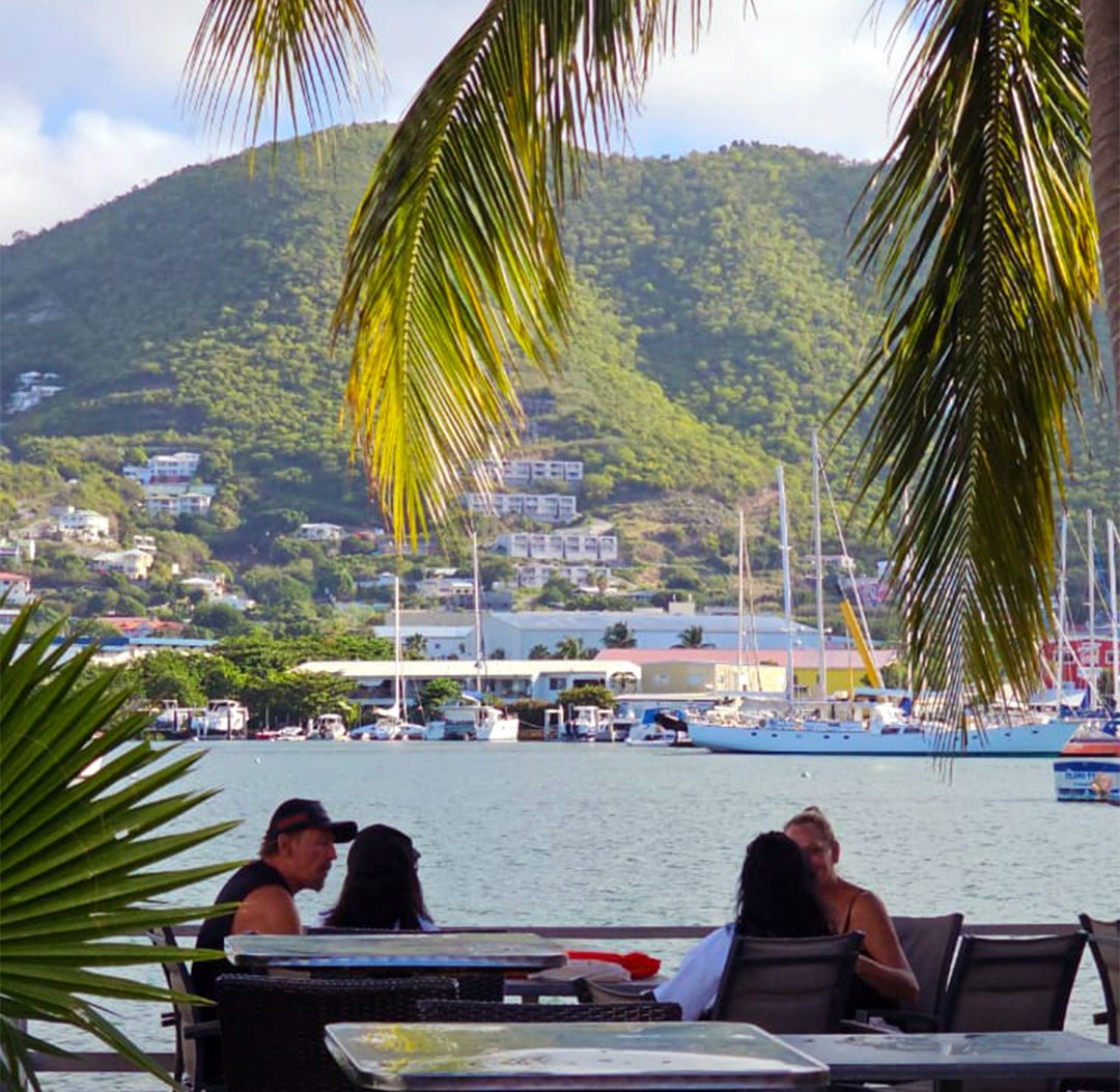 Guests on La Sucrière's waterfront terrace, Simpson Bay Lagoon and the hills behind